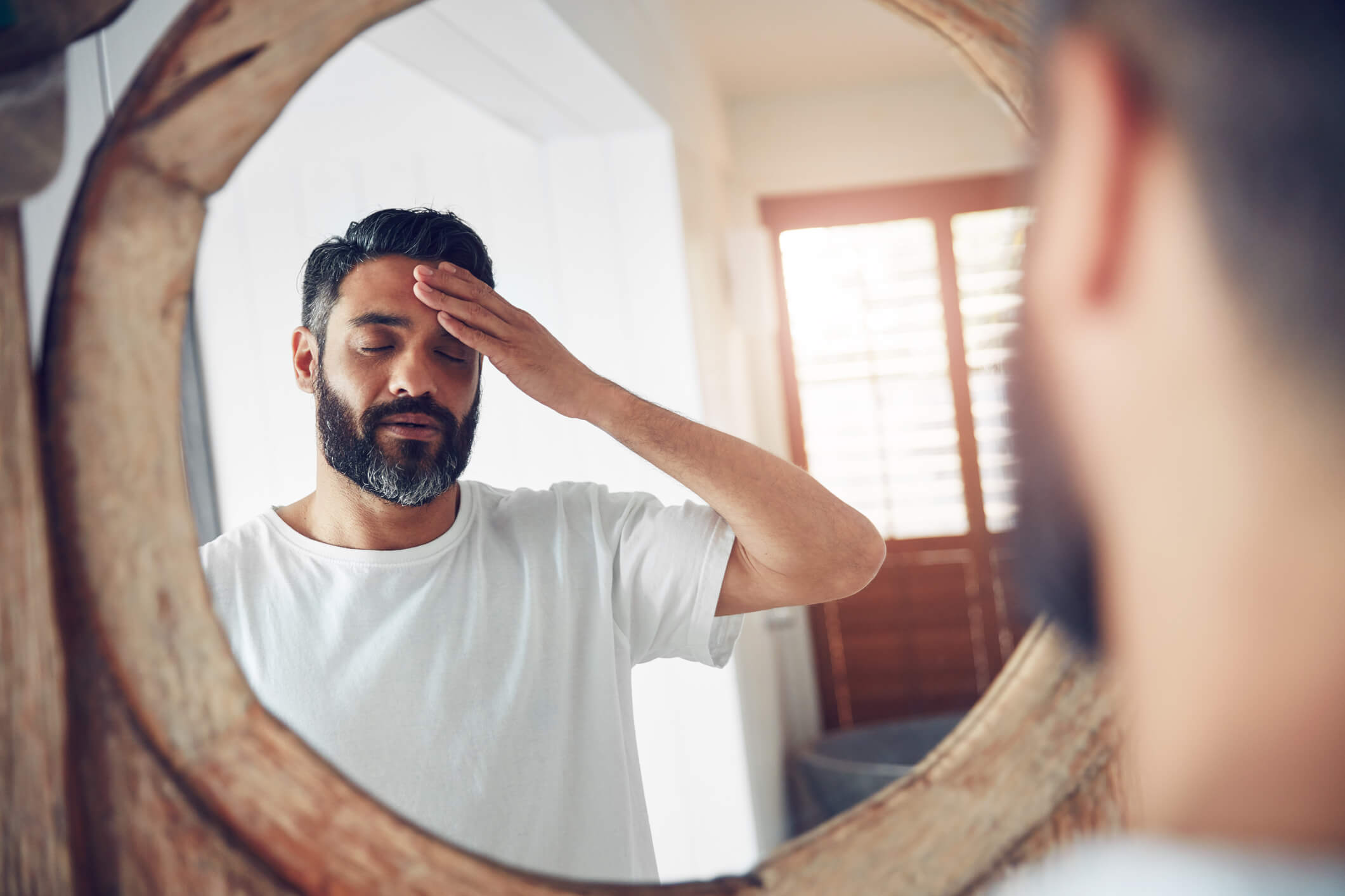 man tired looking in mirror