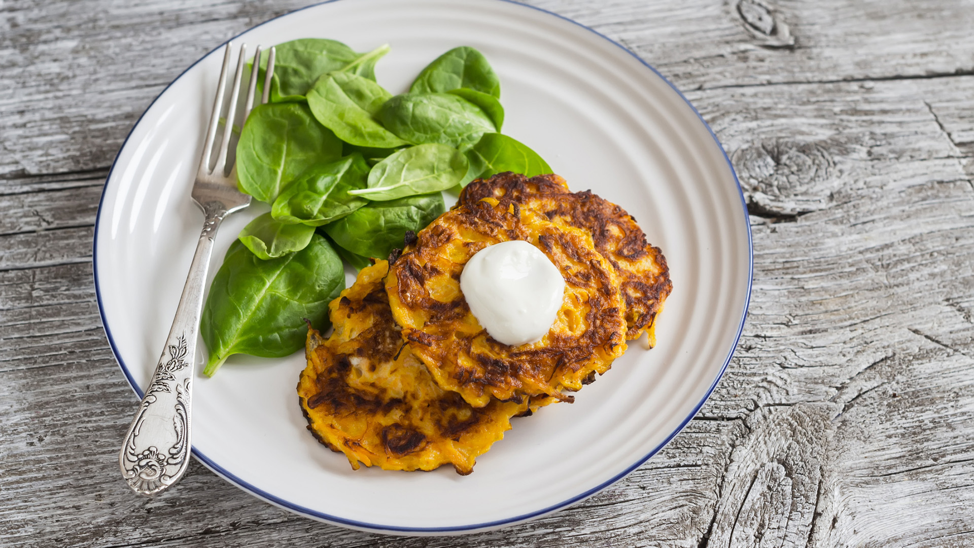 Pumpkin pancakes and fresh spinach on rustic light wooden table