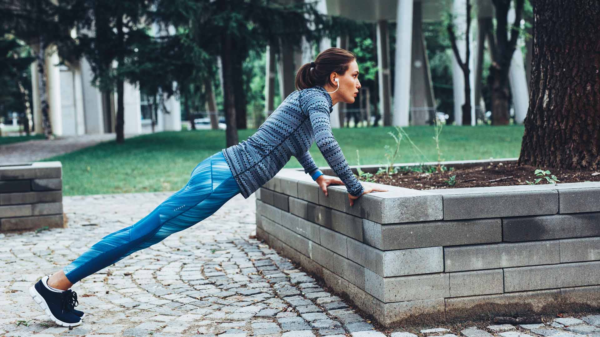 Woman doing pushups outdoor in the city.