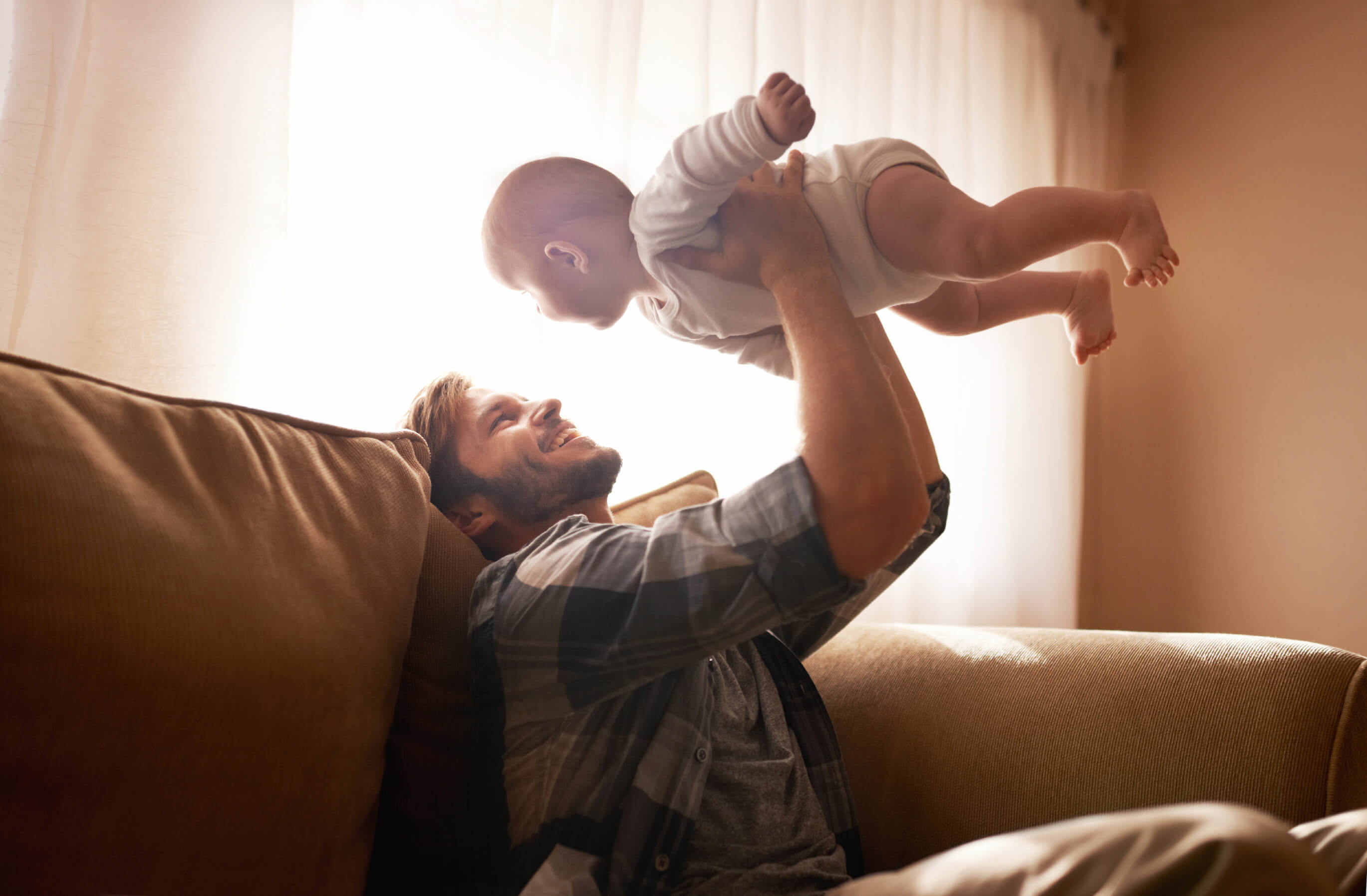 Cropped shot of a father holding his infant child in the air