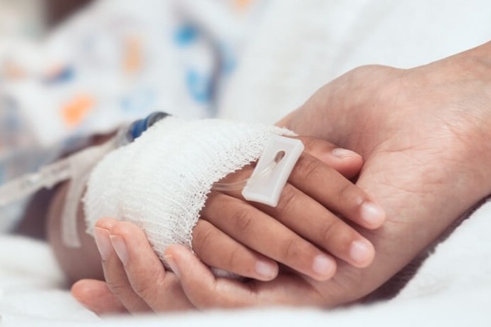 Adult holding child's hand in hospital
