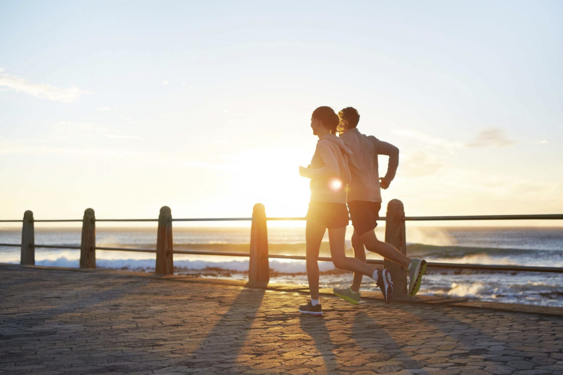 A young couple jogging on the promenade at sunset