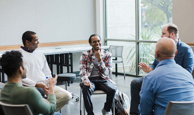 group of men sitting in a circle in a peer support session
