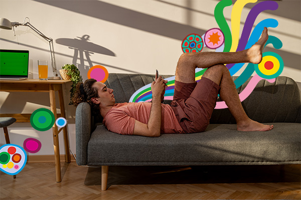 Young man lying on couch using phone