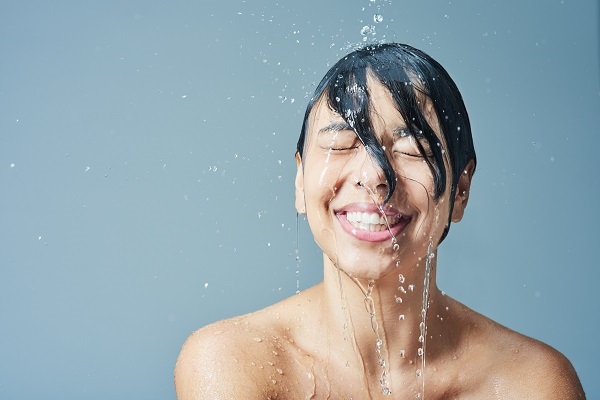 Shot of a young woman having a refreshing shower against a blue background