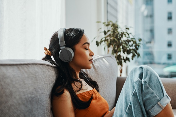 Shot of a young woman using headphones while relaxing on the sofa at home