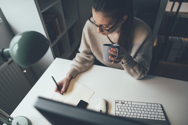1209633602 Young businesswoman easing working long hours with coffee at her home office.