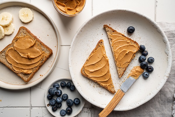 Peanut butter toast with blueberries on ceramic plate
