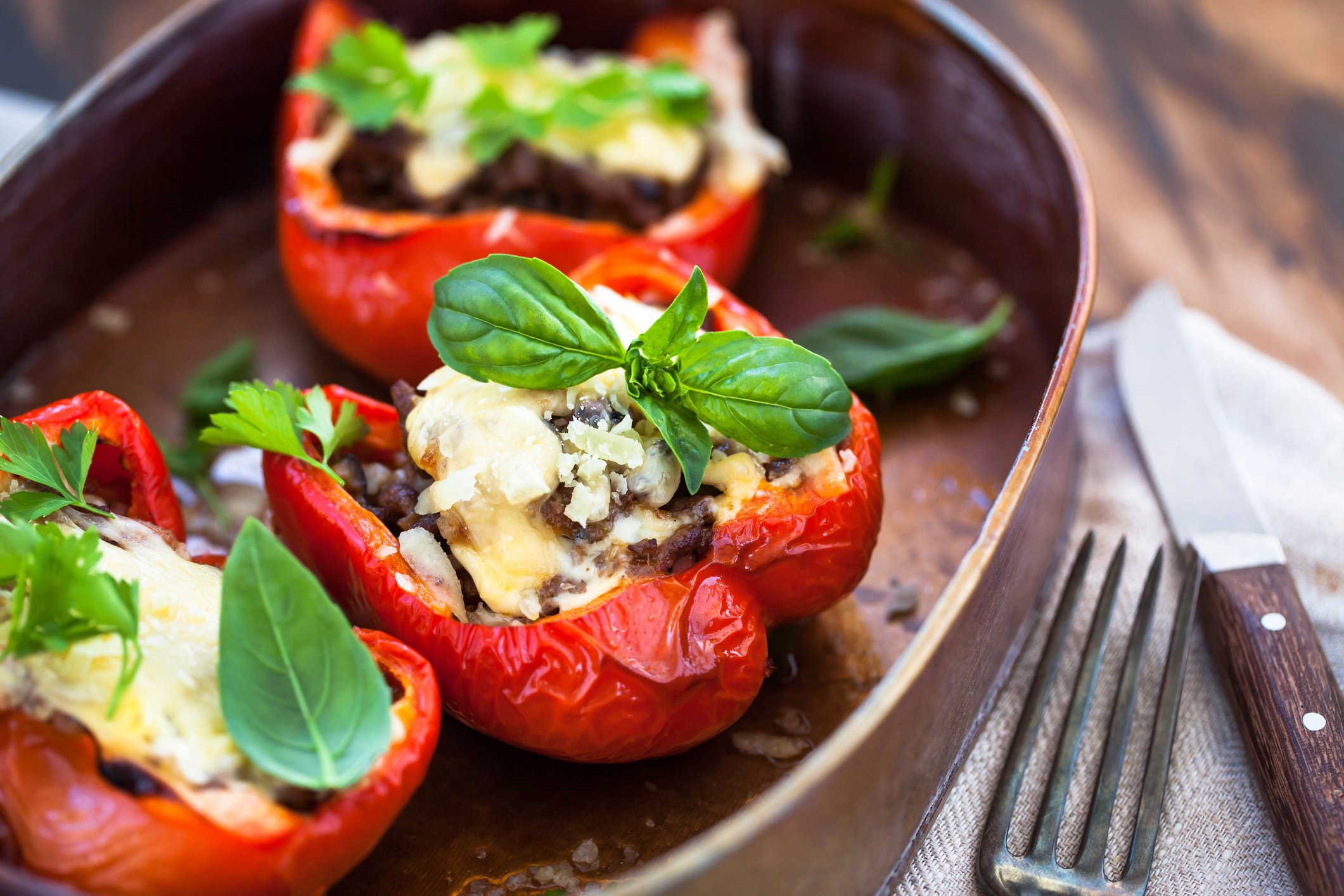 Stuffed bell peppers with ground meat and cheese in baked pot