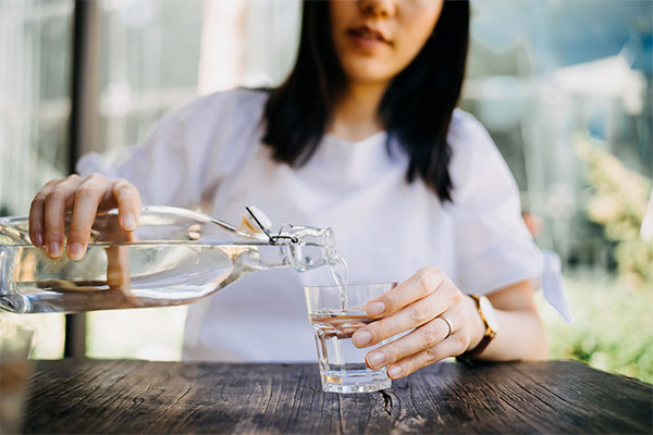 Woman pours water into a glass: being more thirsty than usual is one of the common symptoms of type 2 diabetes.