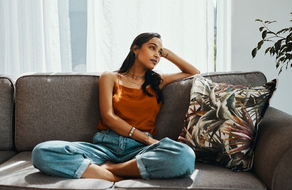 Shot of a young woman looking thoughtful while relaxing on the sofa at home