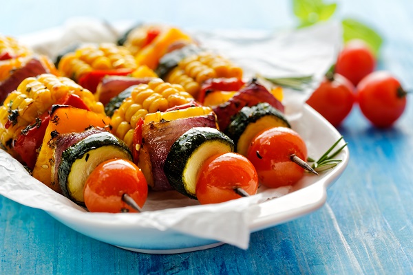 Grilled vegetarian skewers with zucchini, onion, bell pepper, corn and cherry tomatoes in a herb marinade