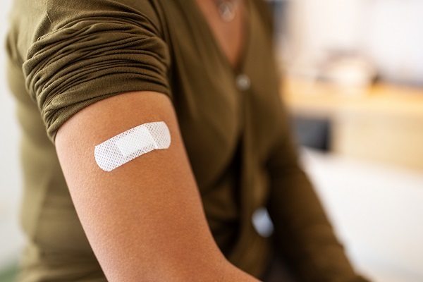 Bandage on arm of a female after taking vaccine. Close-up of a female patient with bandage on hand after taking injection.