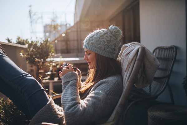 Photo of a young woman taking a few minutes off to relax on the balcony over the city, on a beautiful, sunny, autumn day