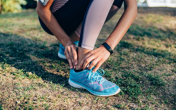 Close-up shot of a young woman holding her injured ankle.