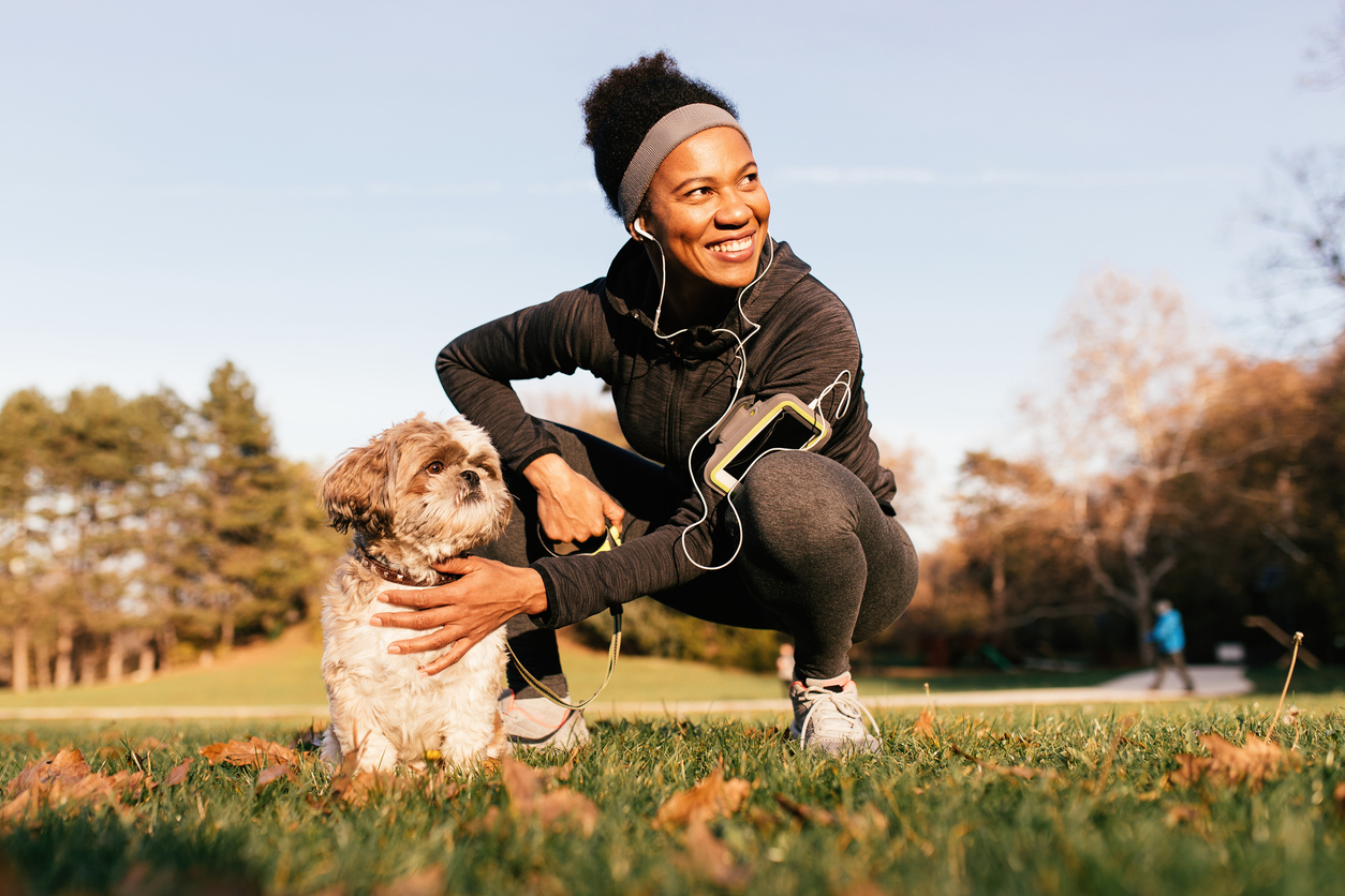 Happy black athletic woman and her dog enjoying in a day in nature.