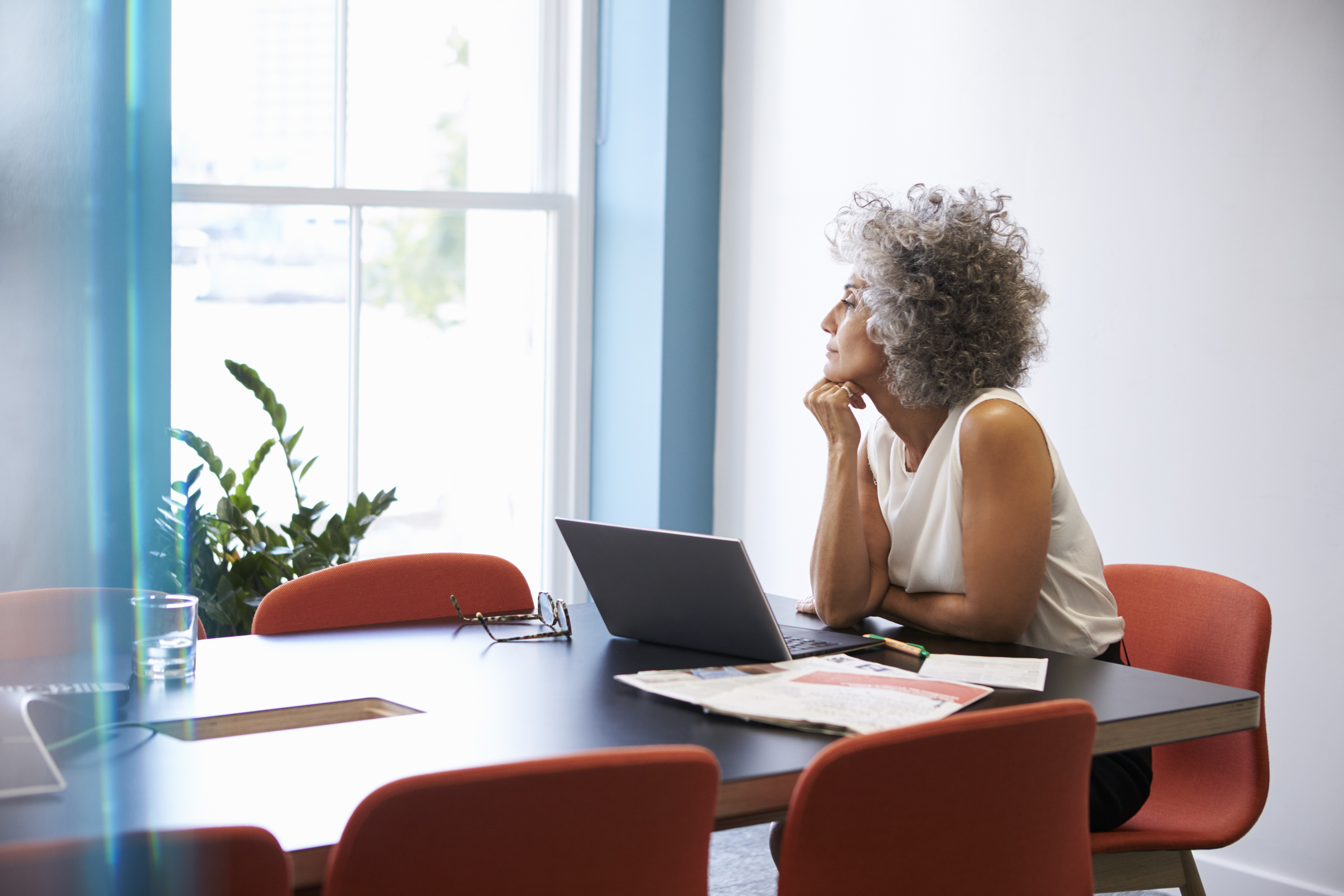 Middle aged woman looking out of the window in the boardroom