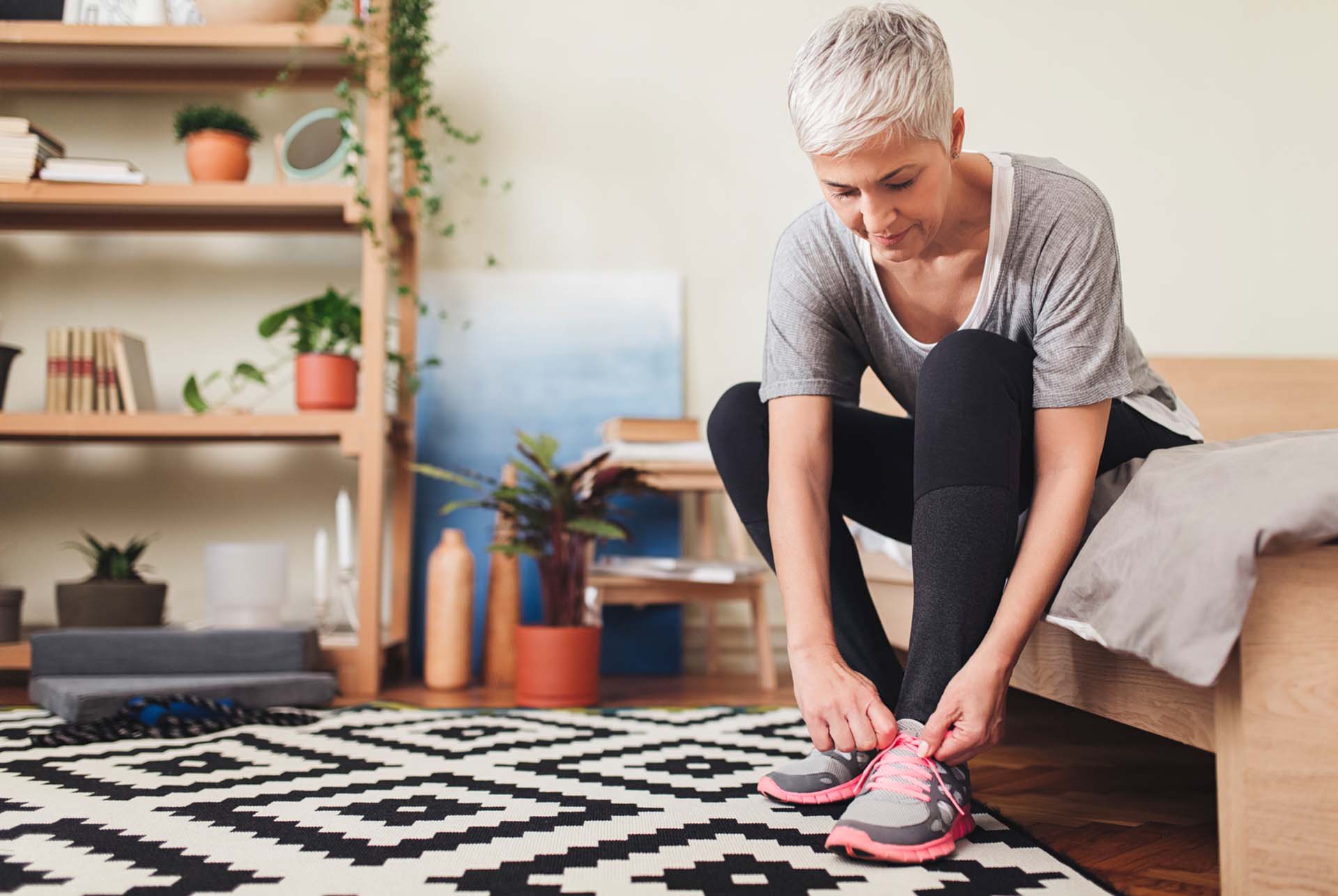 Caucasian senior woman tying the laces on her running sneakers.