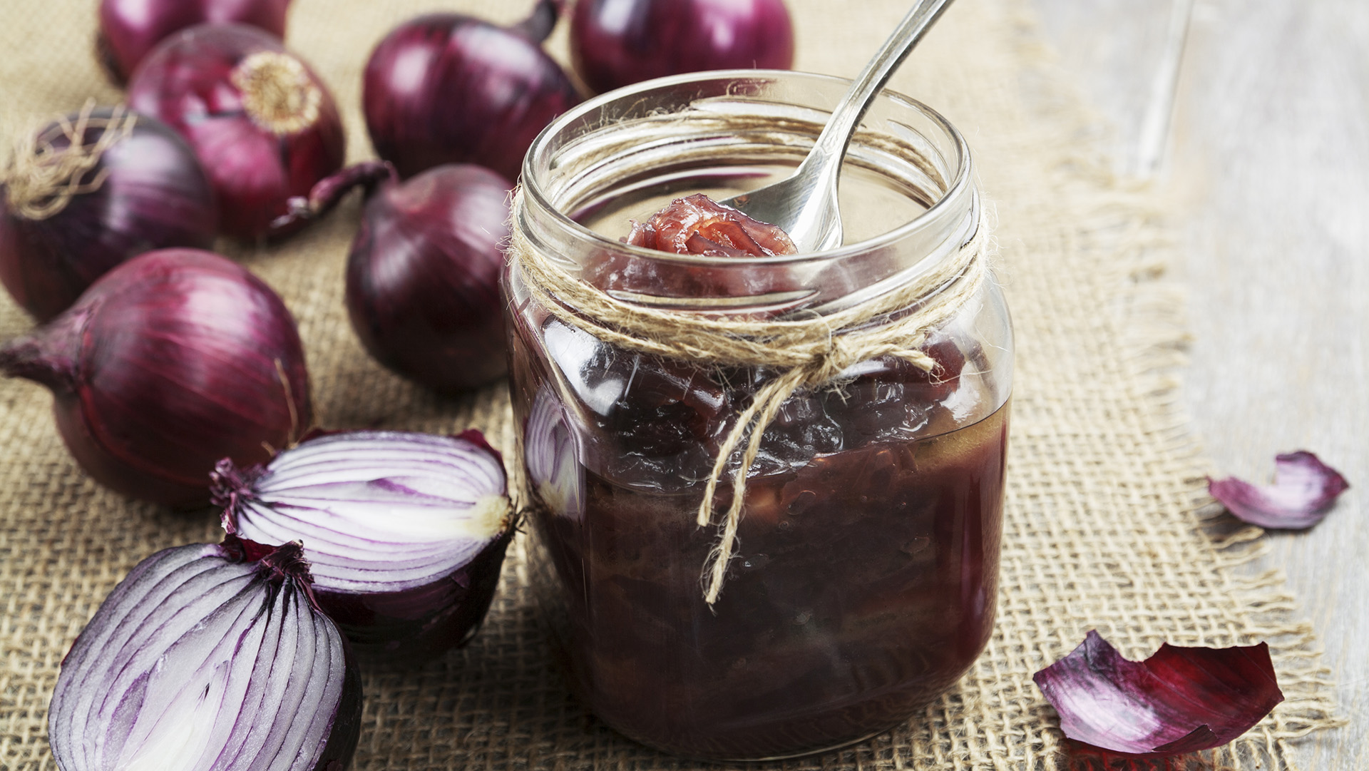 Onion jam in a glass jar on a wooden table