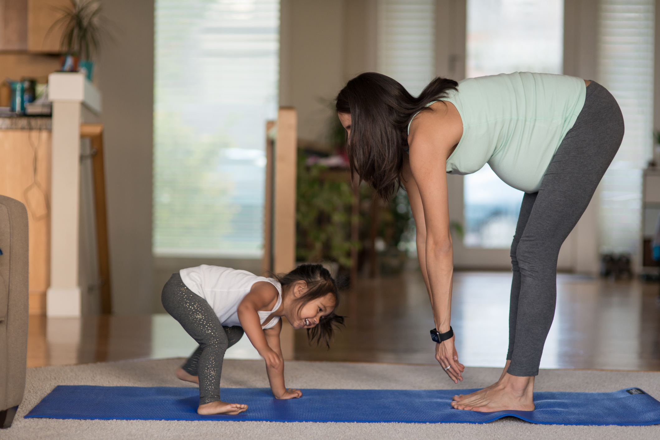 Ethnic pregnant mother doing yoga with her young toddler at home