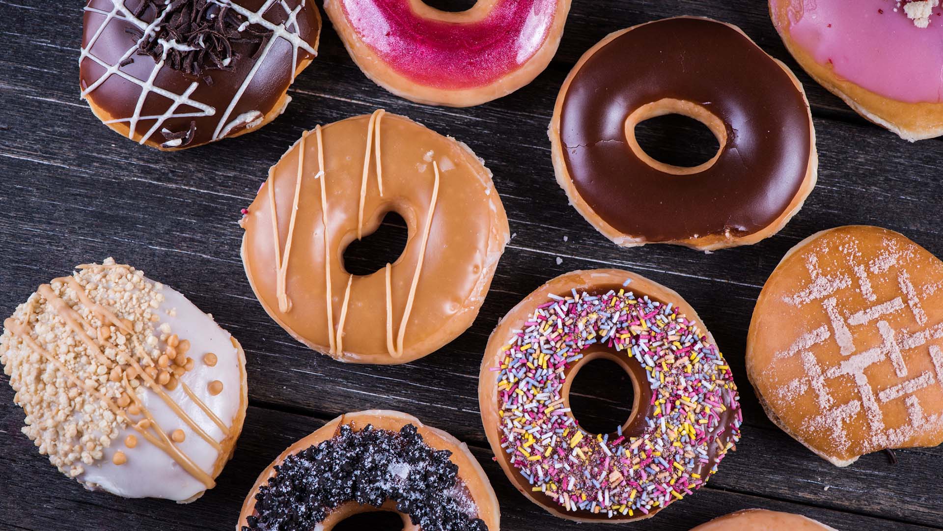 Hand decorated artisan donuts on wooden rustic table, from above