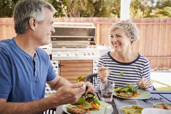 Senior white couple eating together at a table in the garden