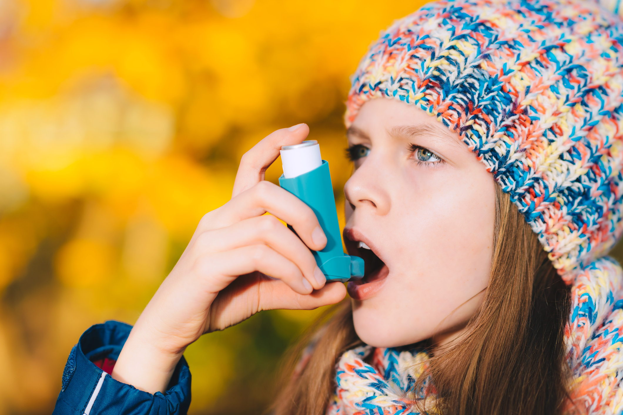 Asthma patient girl inhaling medication for treating shortness of breath and wheezing in a park. Chronic disease control, allergy induced asthma remedy and allergy disease concept