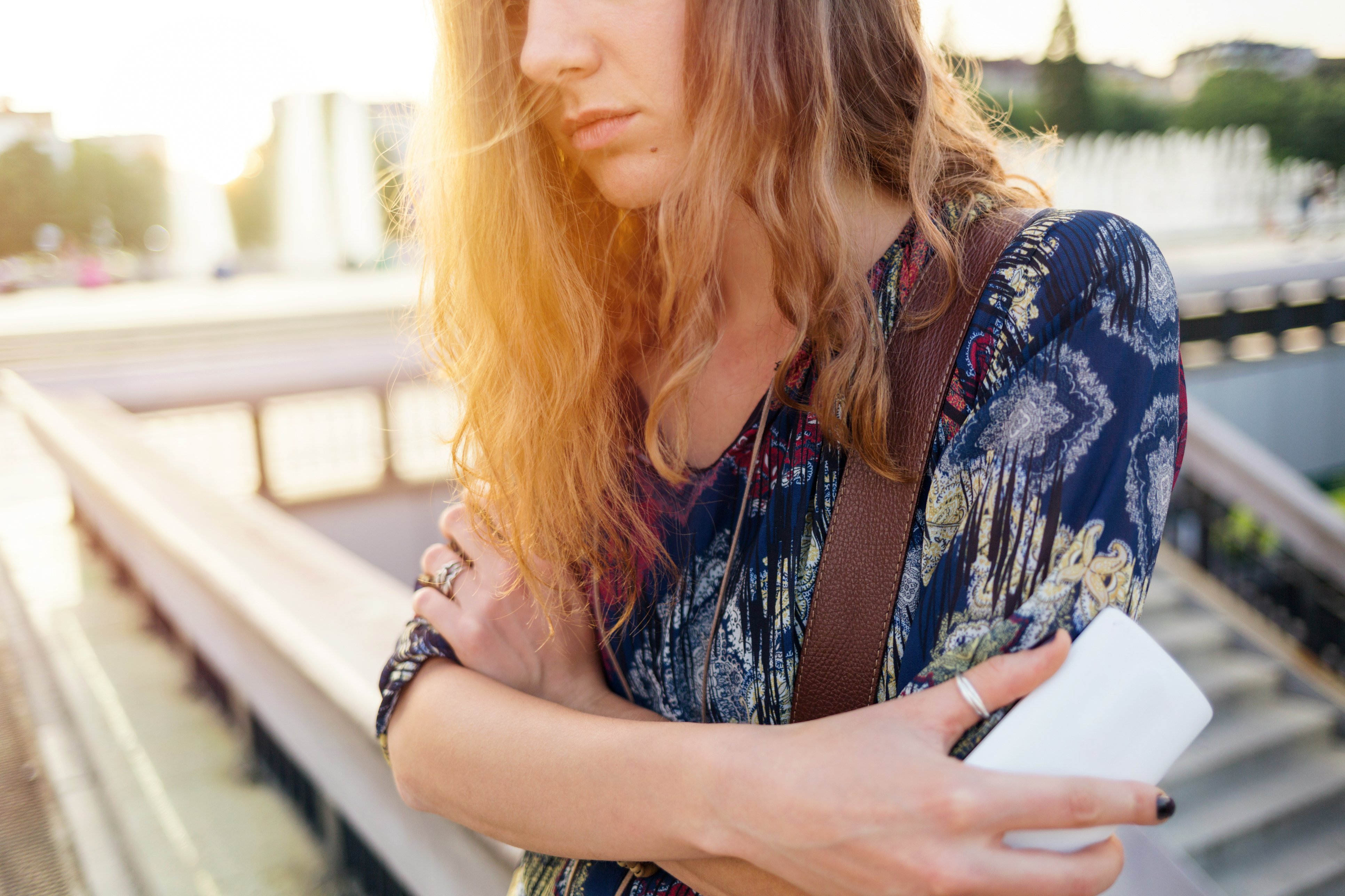 Teenage girl feeling depressed. Casually dressed and holding smart phone with left hand. Creative crop - no face.