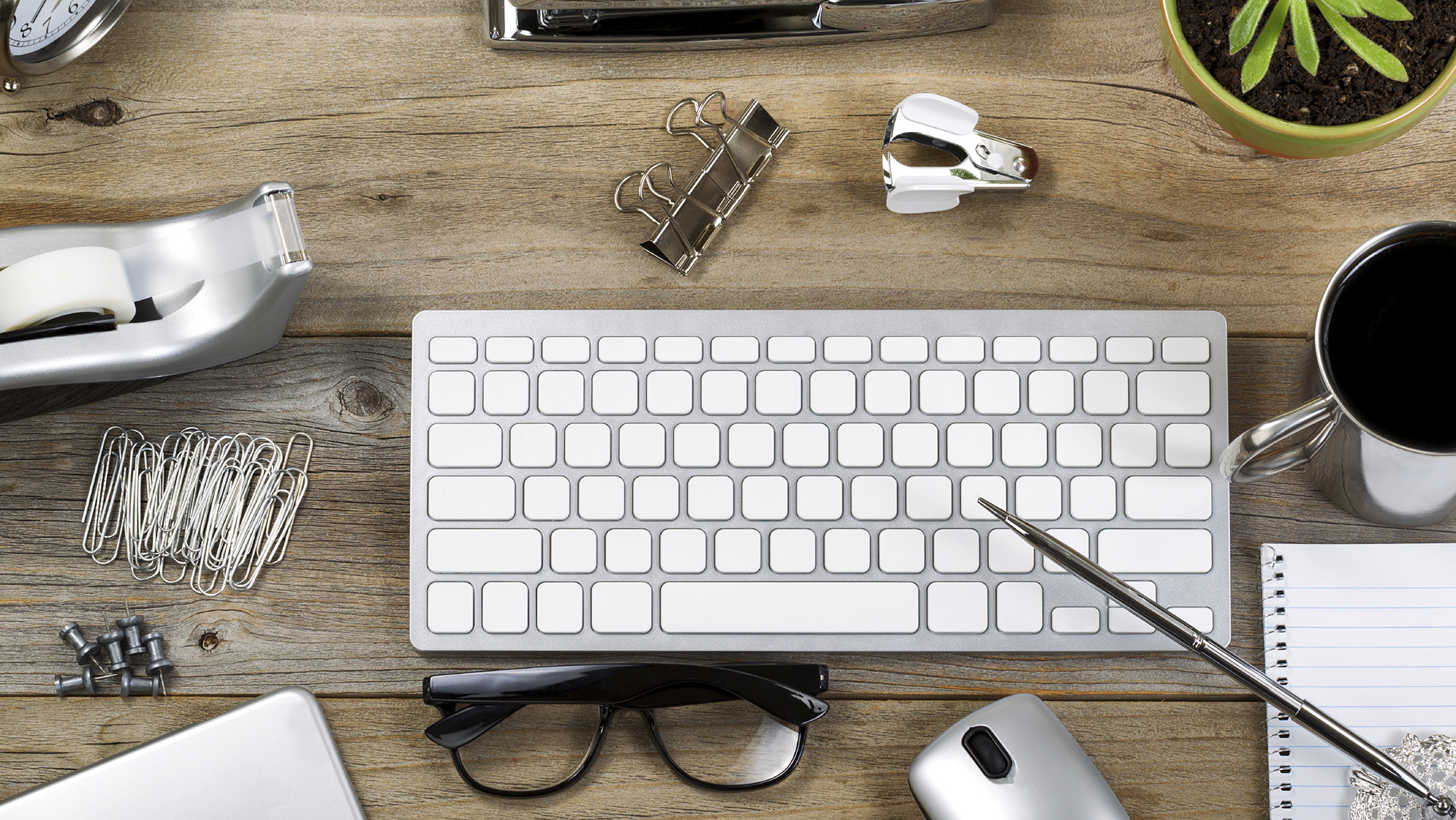 Rustic desktop with work accessories. Objects in and out of frame layout with mostly silver color items.