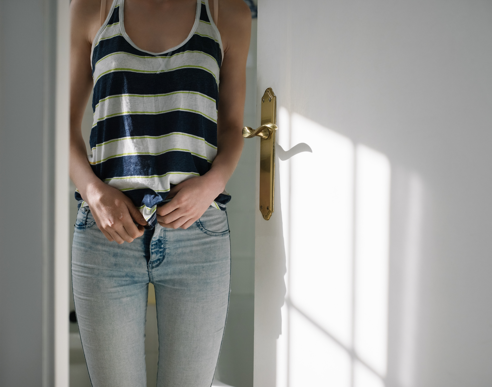 Woman unbuttoning jeans at home