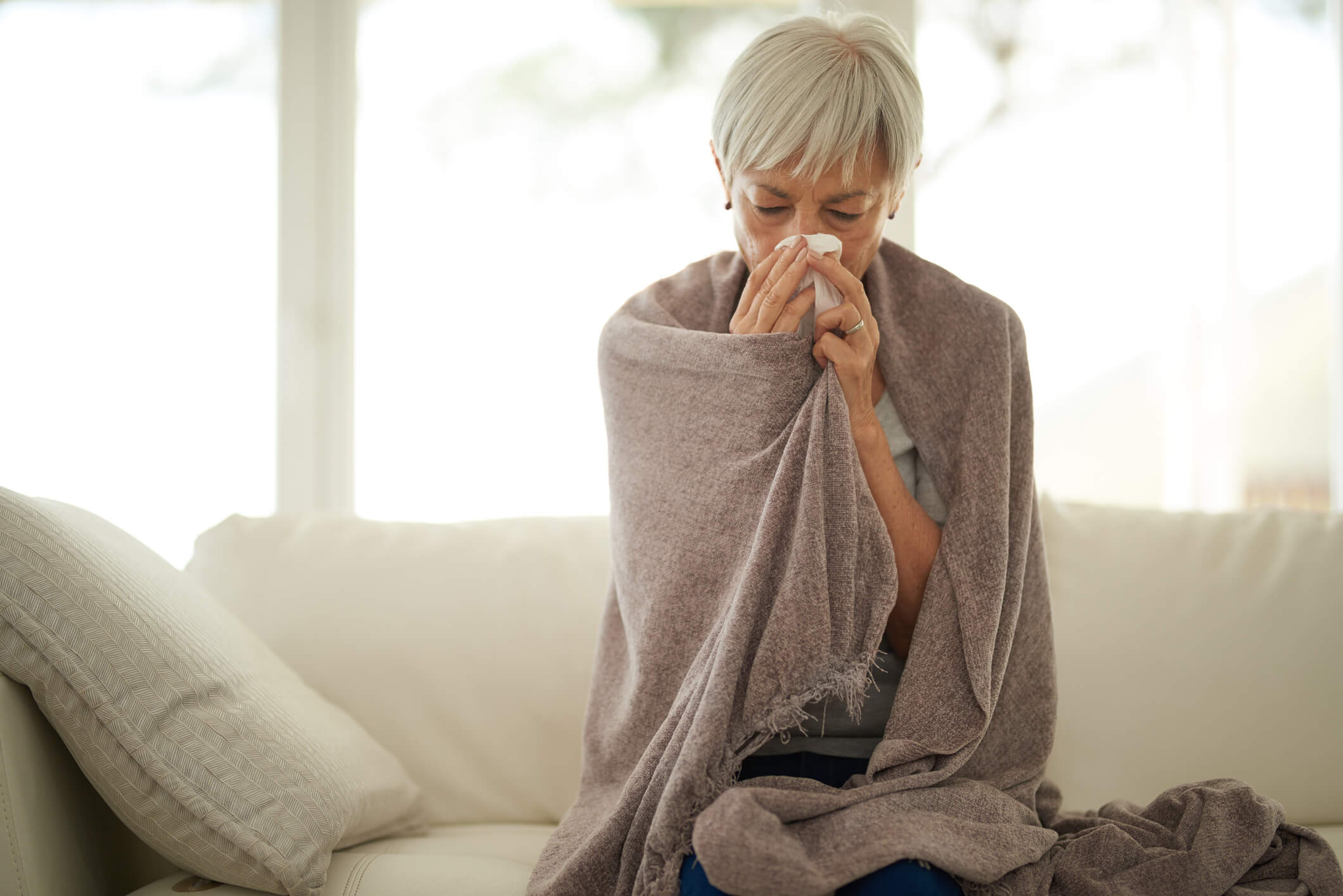 Woman with the flu rubbing her nose with a tissue