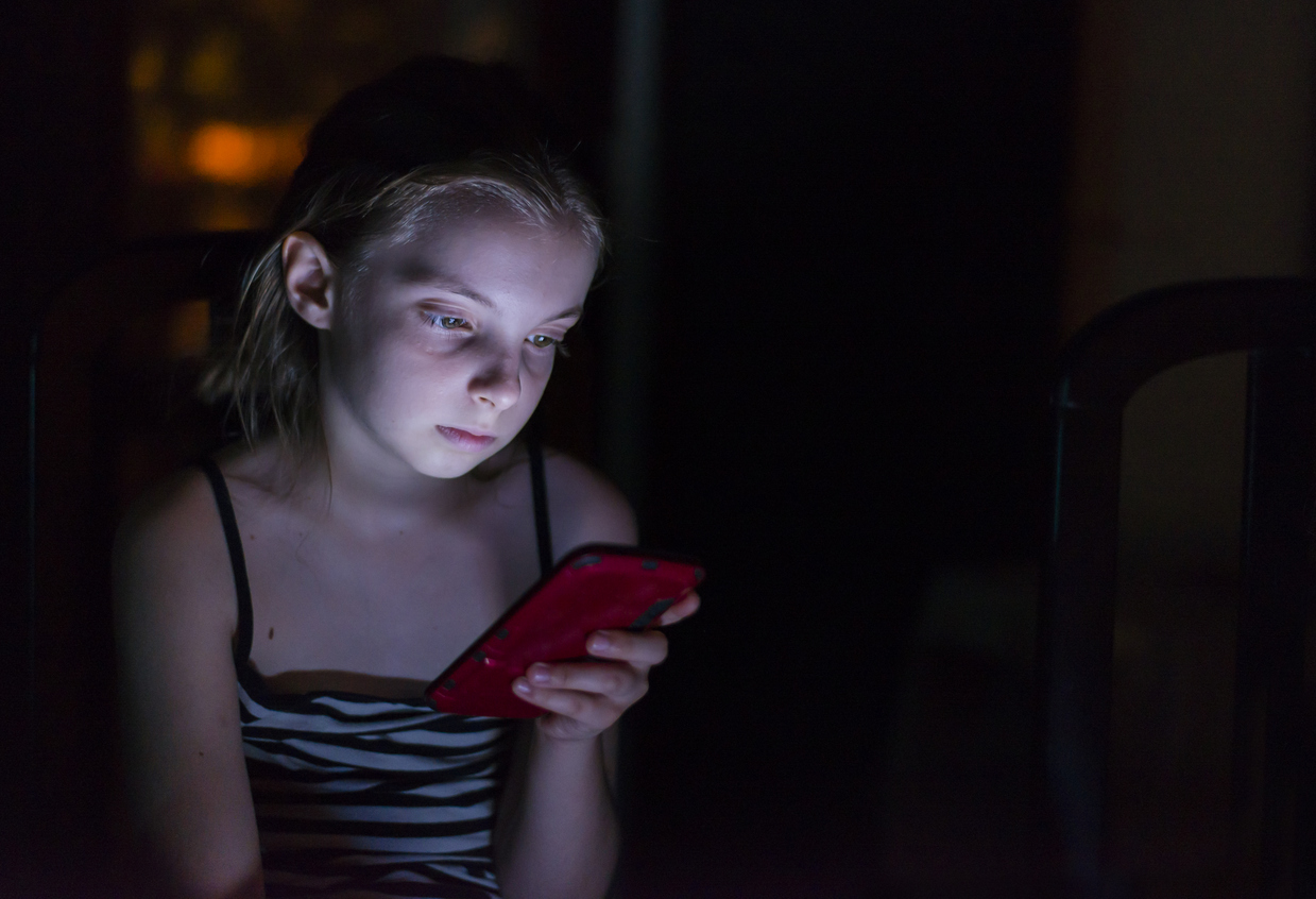 Teenager checks her mobile phone in bed during the night. technology, internet, communication and people concept - close up of teen girl texting on smartphone at home at night.  Internet Addiction Disorder