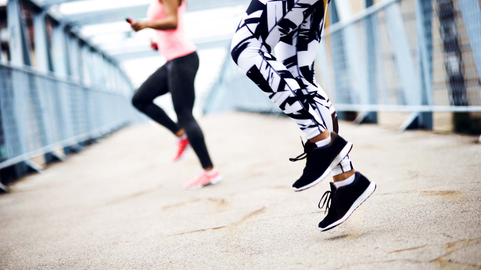 Two unrecognizable woman jumping rope in urban environment