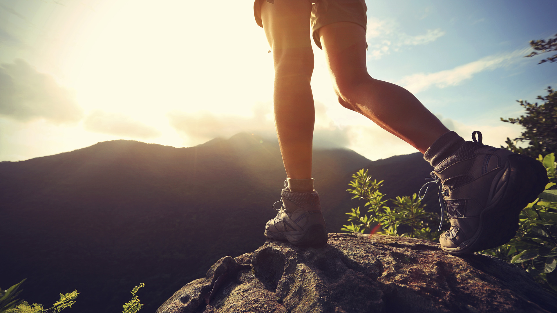 woman hiker legs stand on mountain peak rock