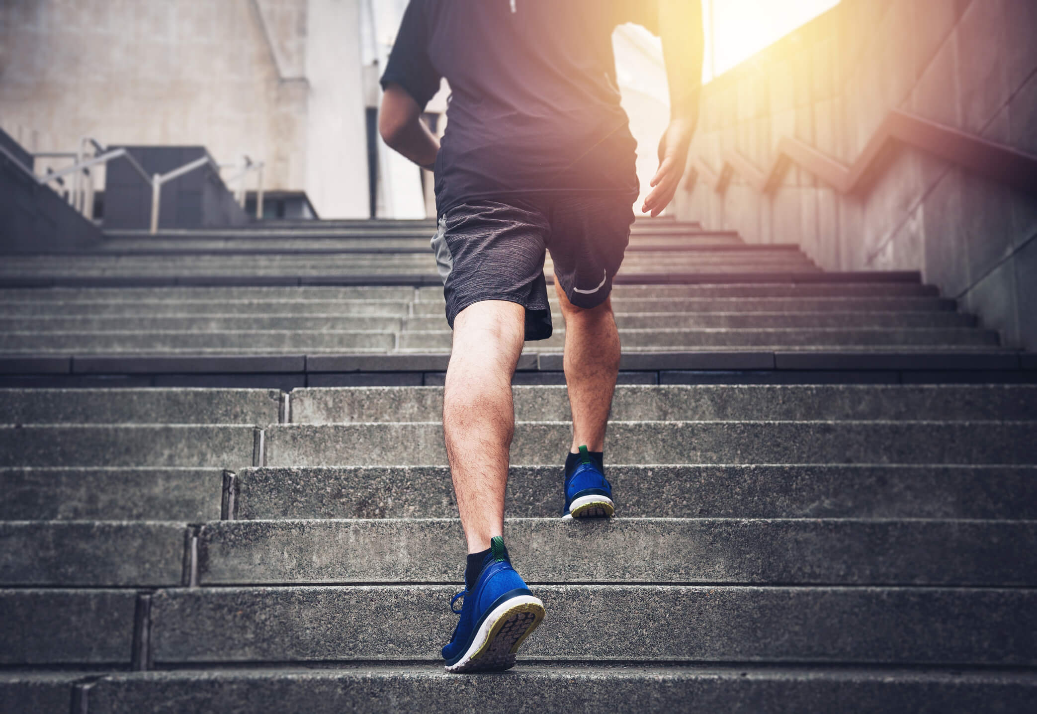 Man running up concrete stairs during workout.