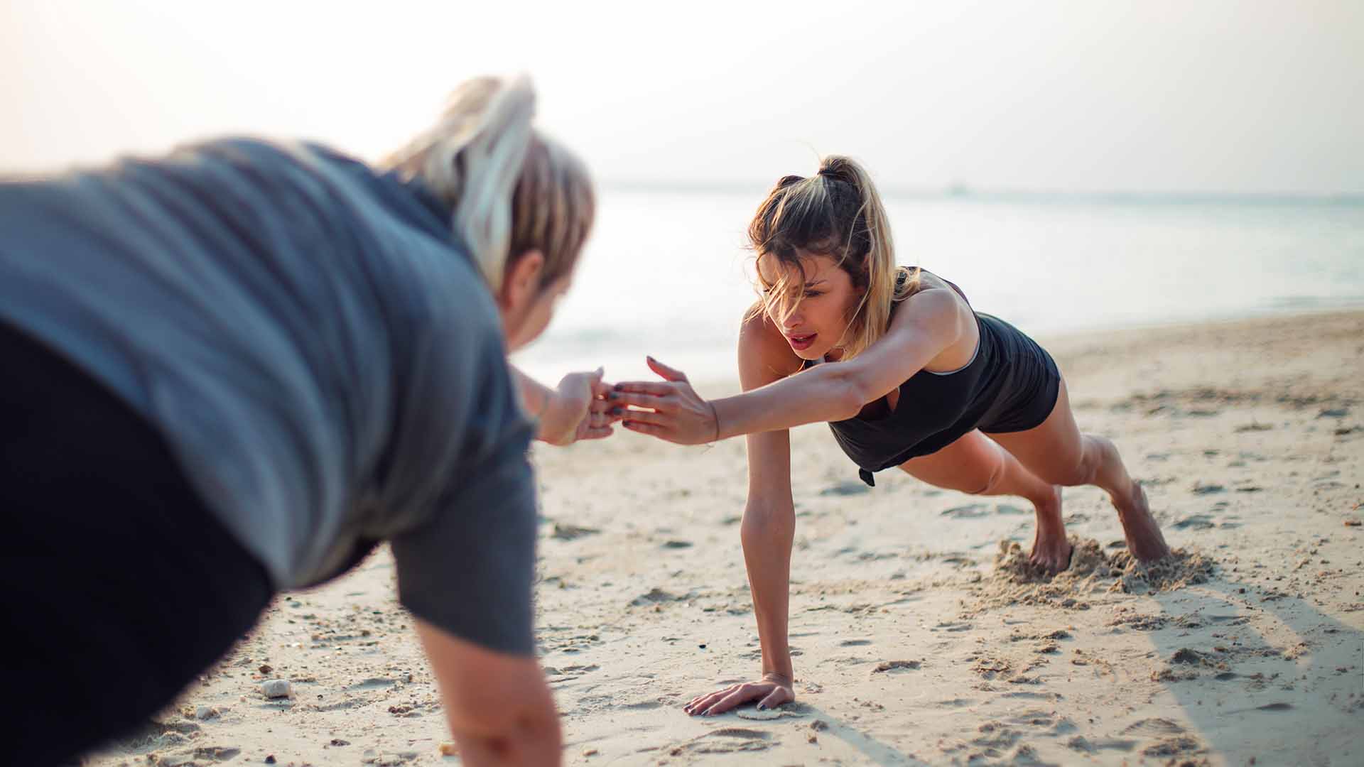 Two beautiful girls working out together on the beach