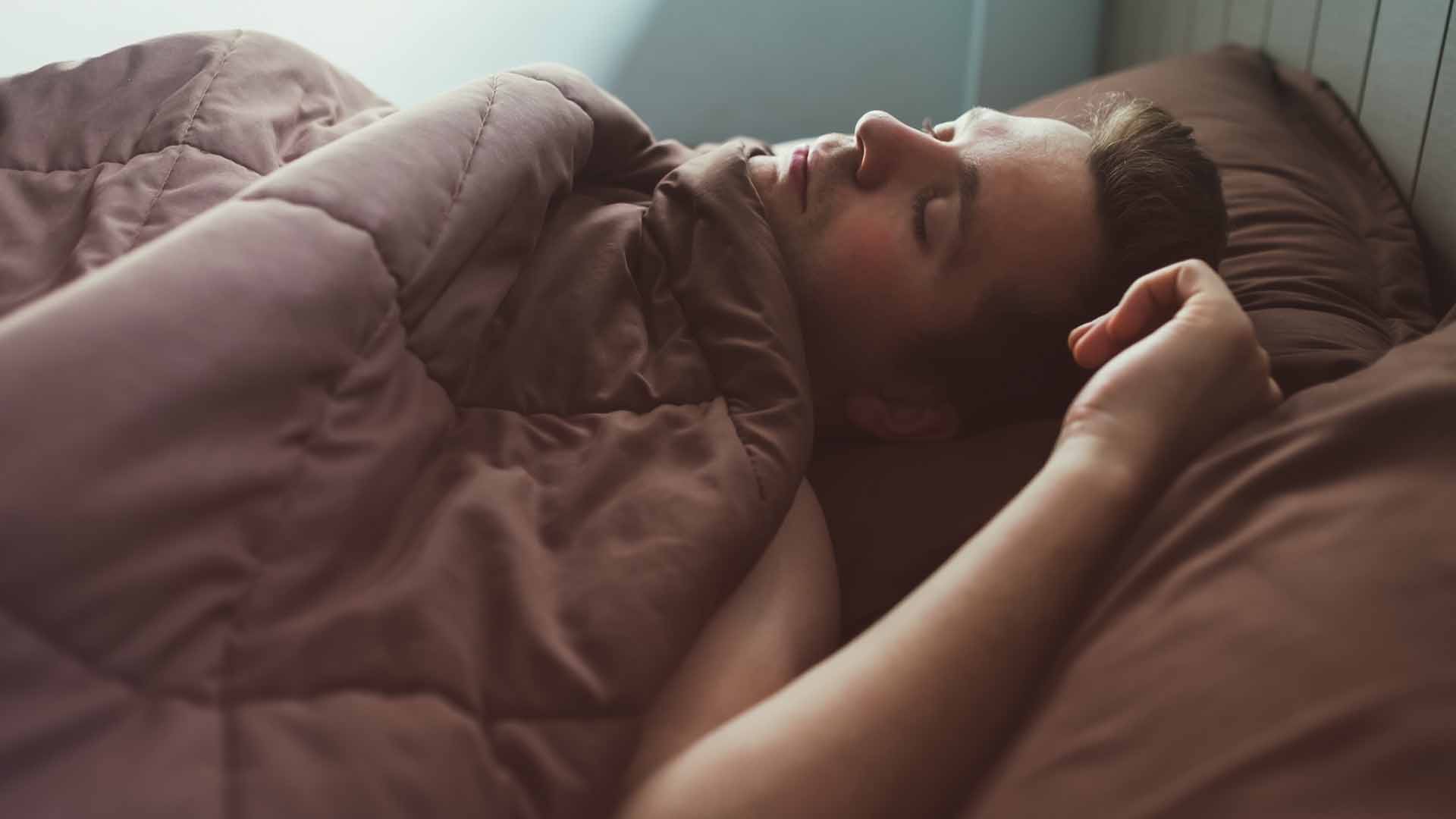 Caucasian man napping in bed in the morning. Soft light of sun.