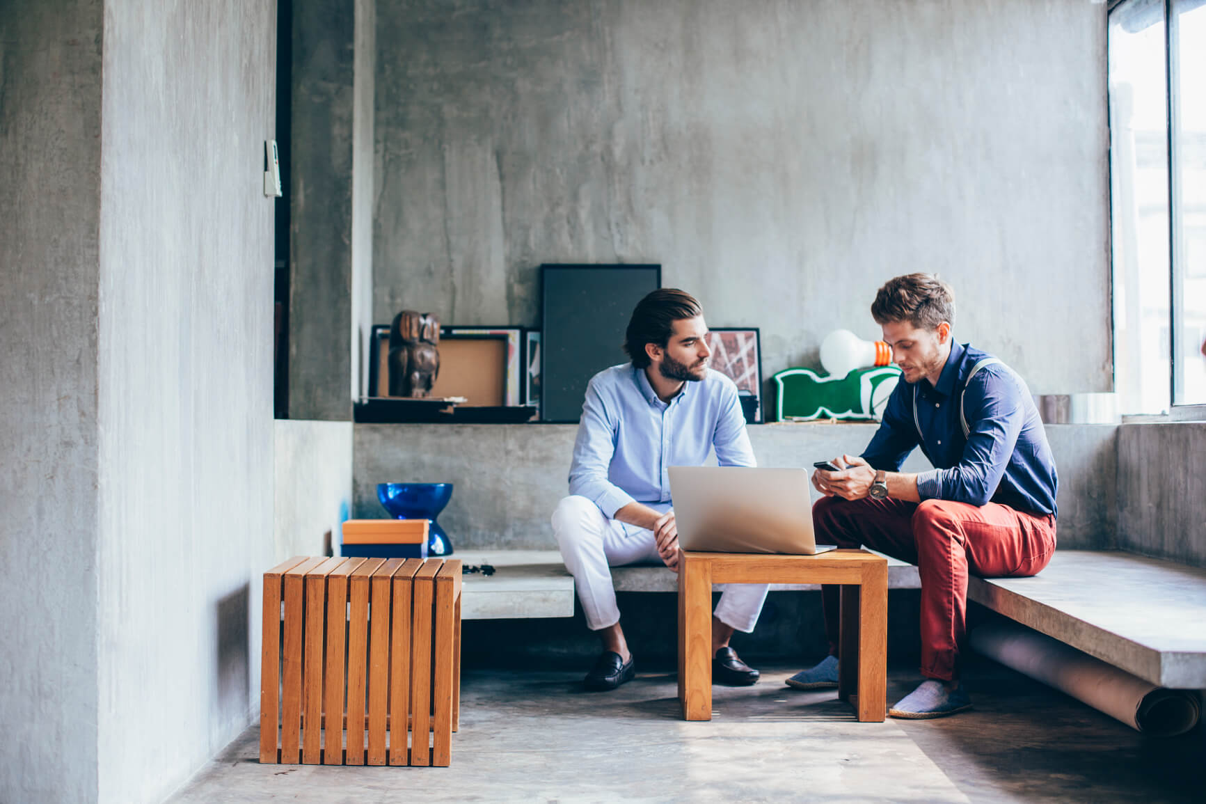 2 men sitting in front of a laptop talking