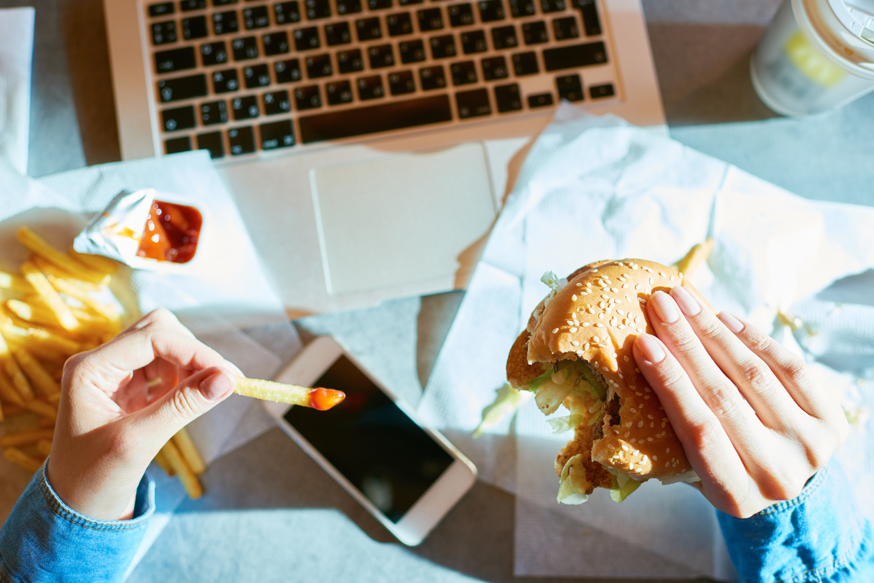 Female hands holding bitten hamburger and dipped French fries