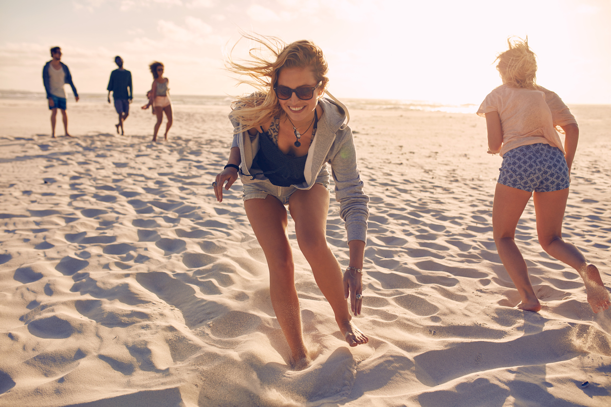 Young women running race on the beach. Group of young people playing games on sandy beach on a summer day. Having fun on the beach.