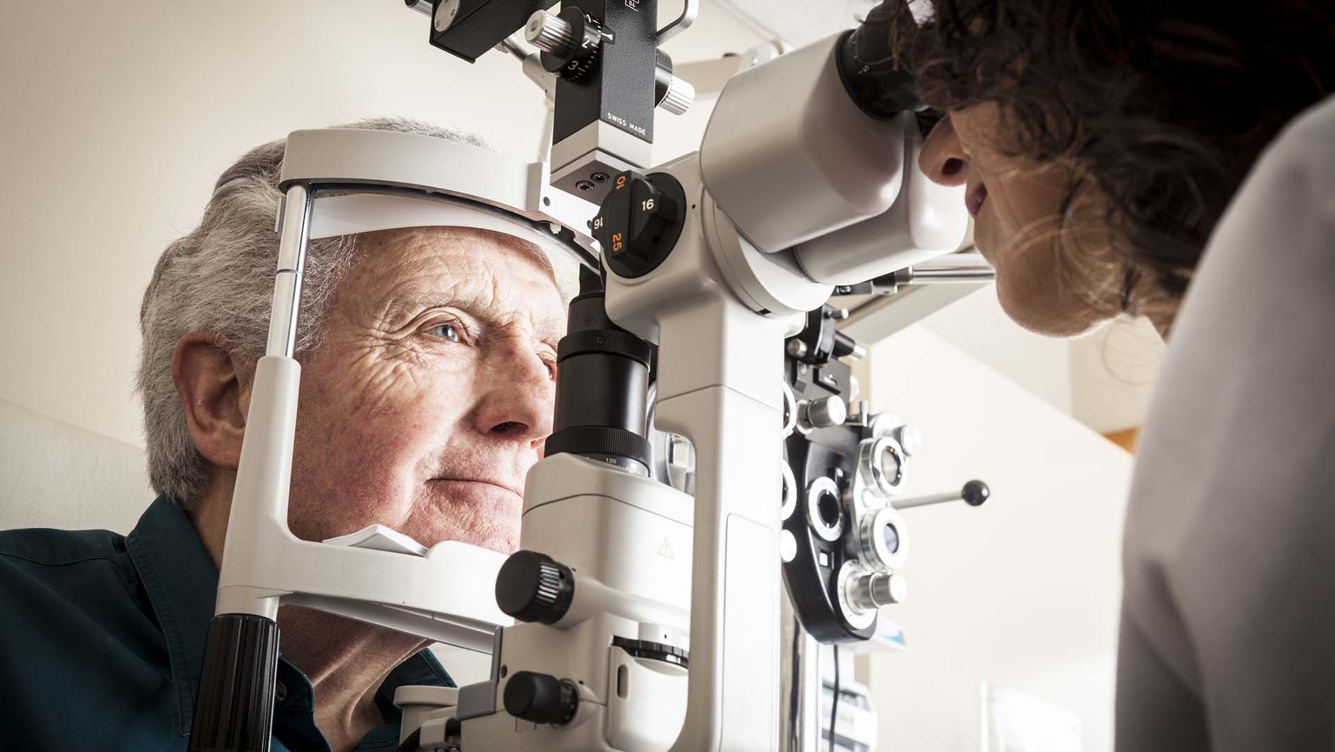 Optometrist giving eye exam to senior patient