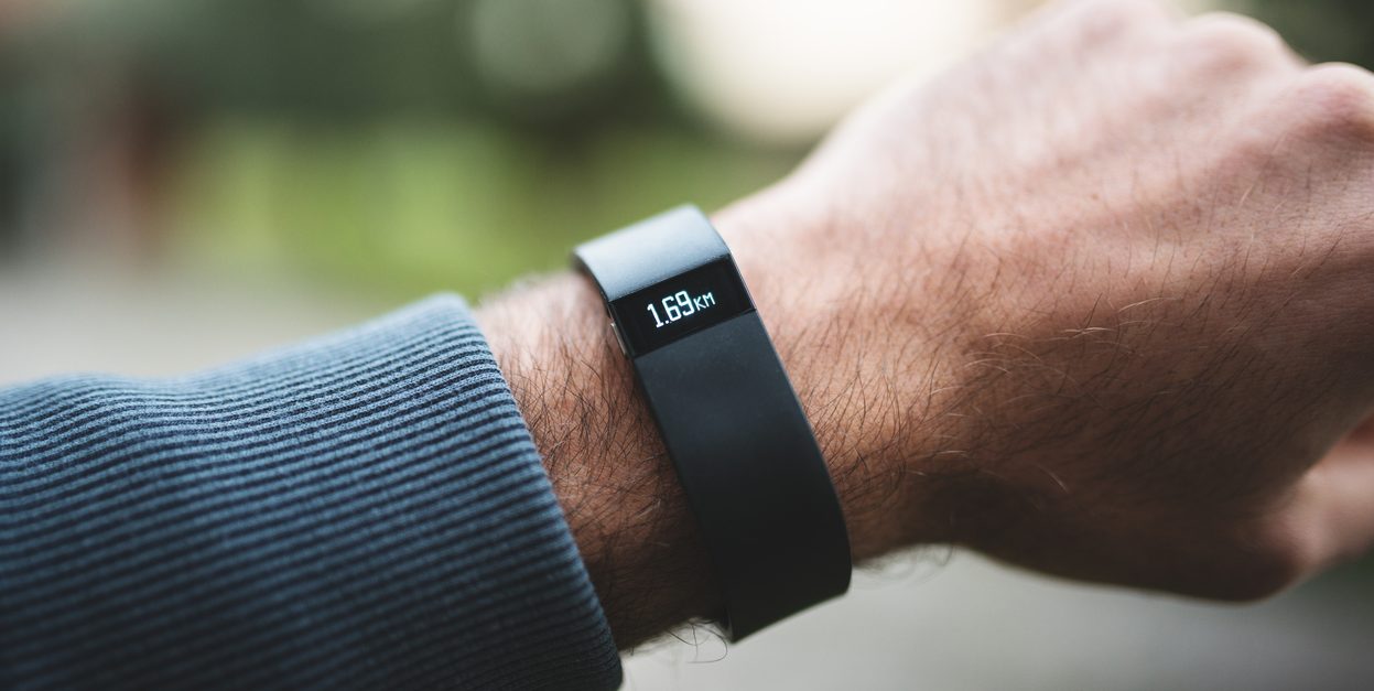 Florence, Italy - January 26, 2014: Close up of the new Fitbit Force on the wrist of a guy. Fitbit Force is the new sport fitness tracker that can allow to track your daily activity, calories burned, sleep &amp; weight, and with that is it possible the upload wirelessly &amp; see progress on mobile and online dashboard. The bracelet is showing the number of daily kms done. image taken outdoor.