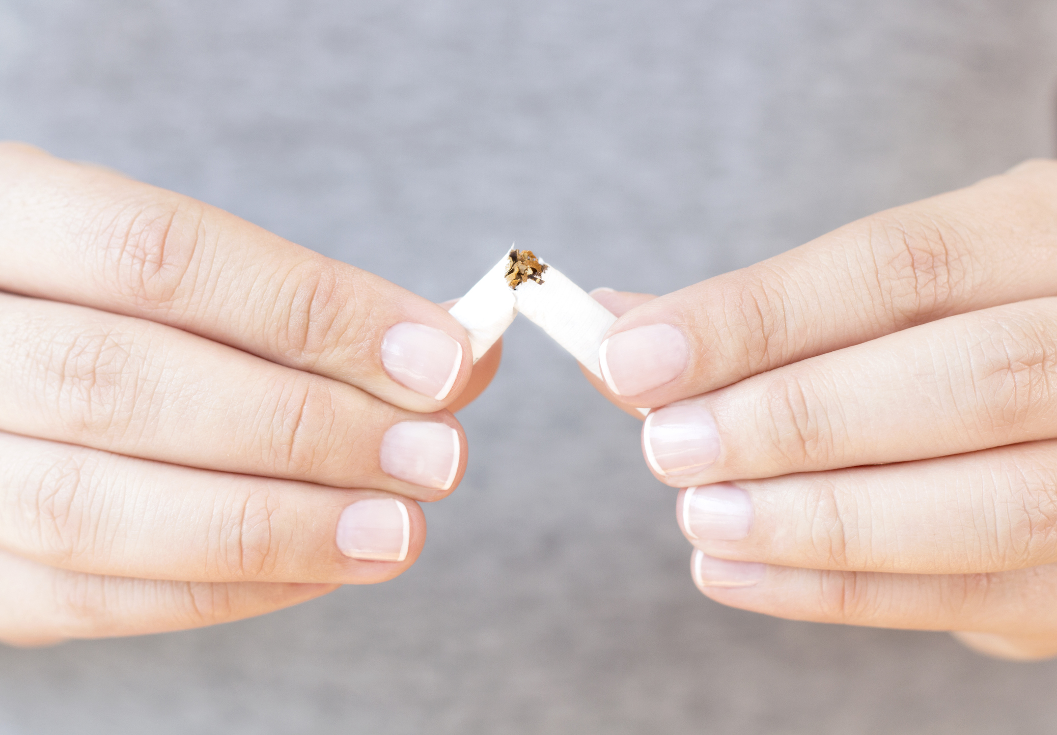 Caucasian female is breaking a cigarette.