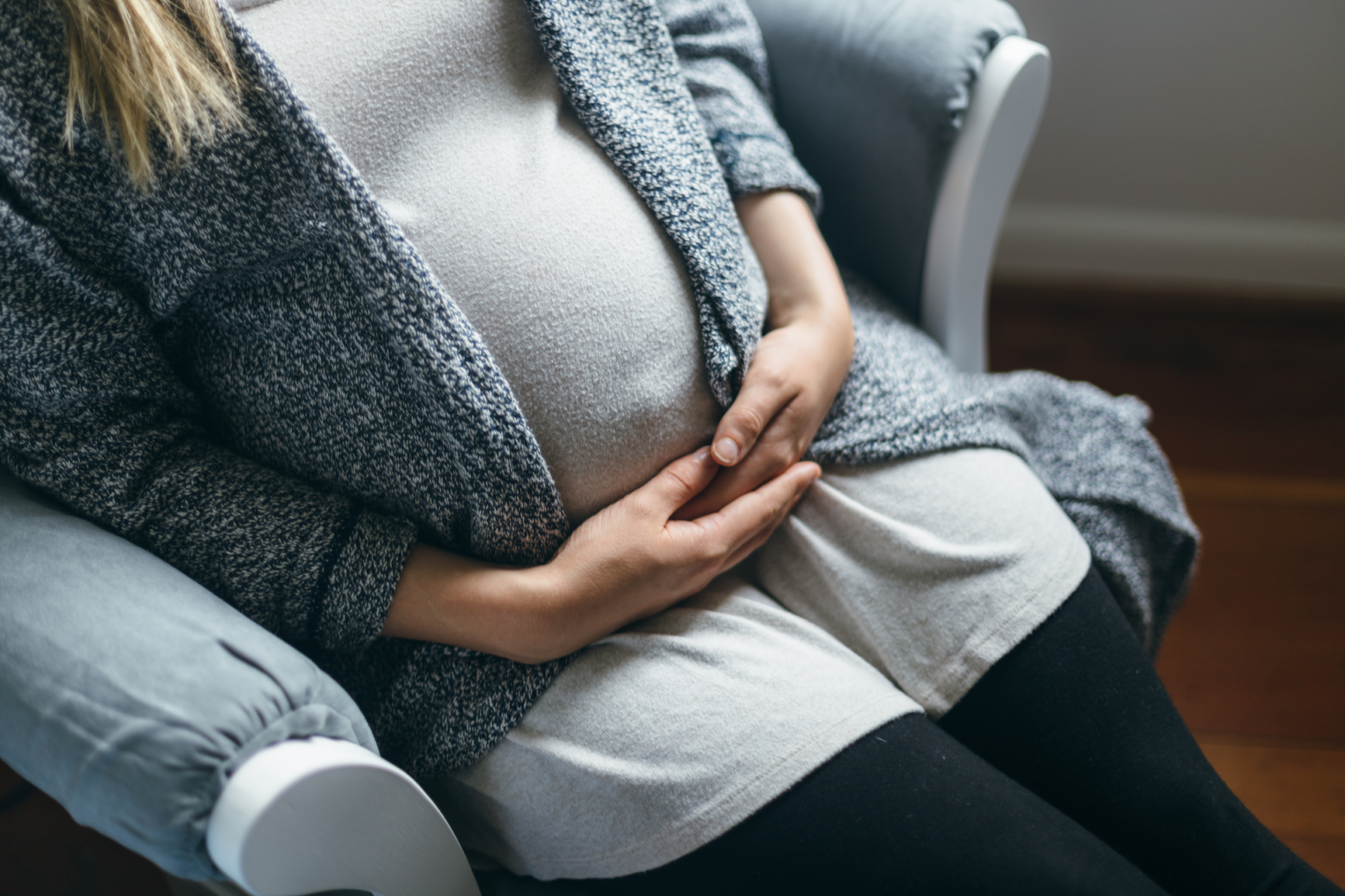 Full Term Pregnant Mother Sitting in Rocking Chair Patiently Waiting For Baby To Arrive