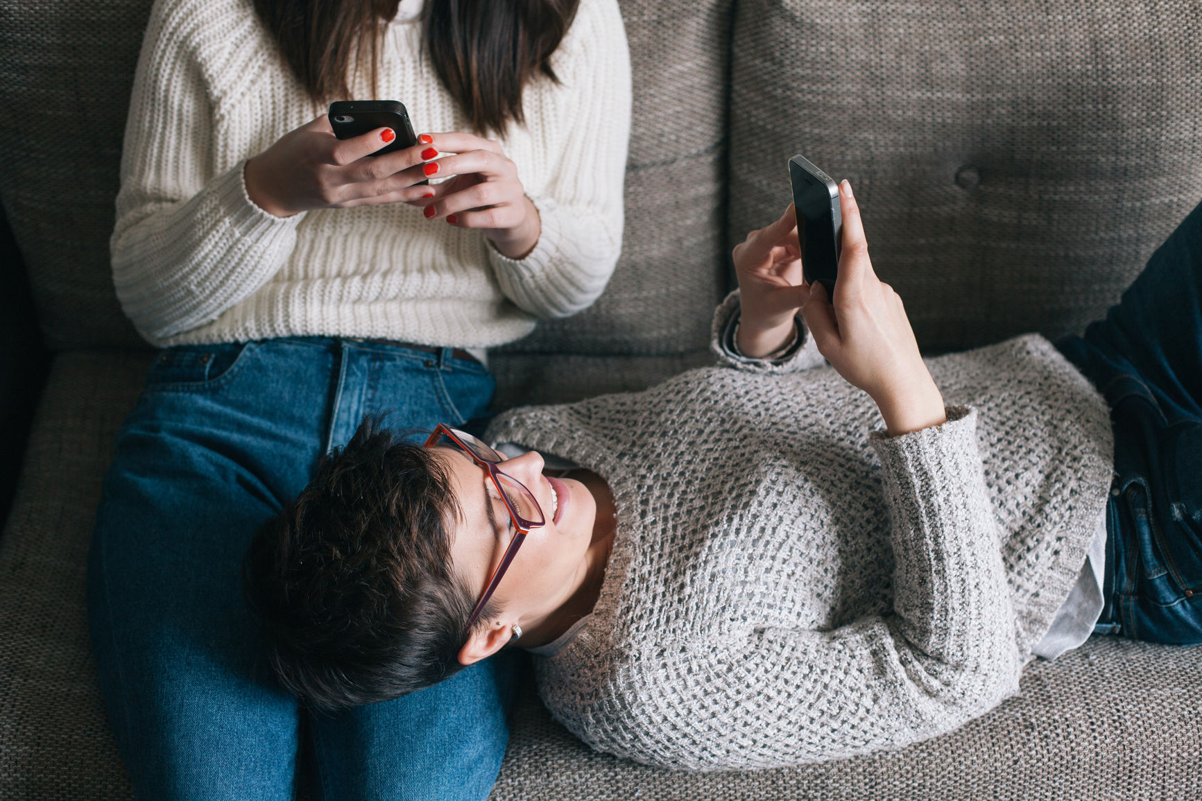 Two female friends browsing on their mobile phones