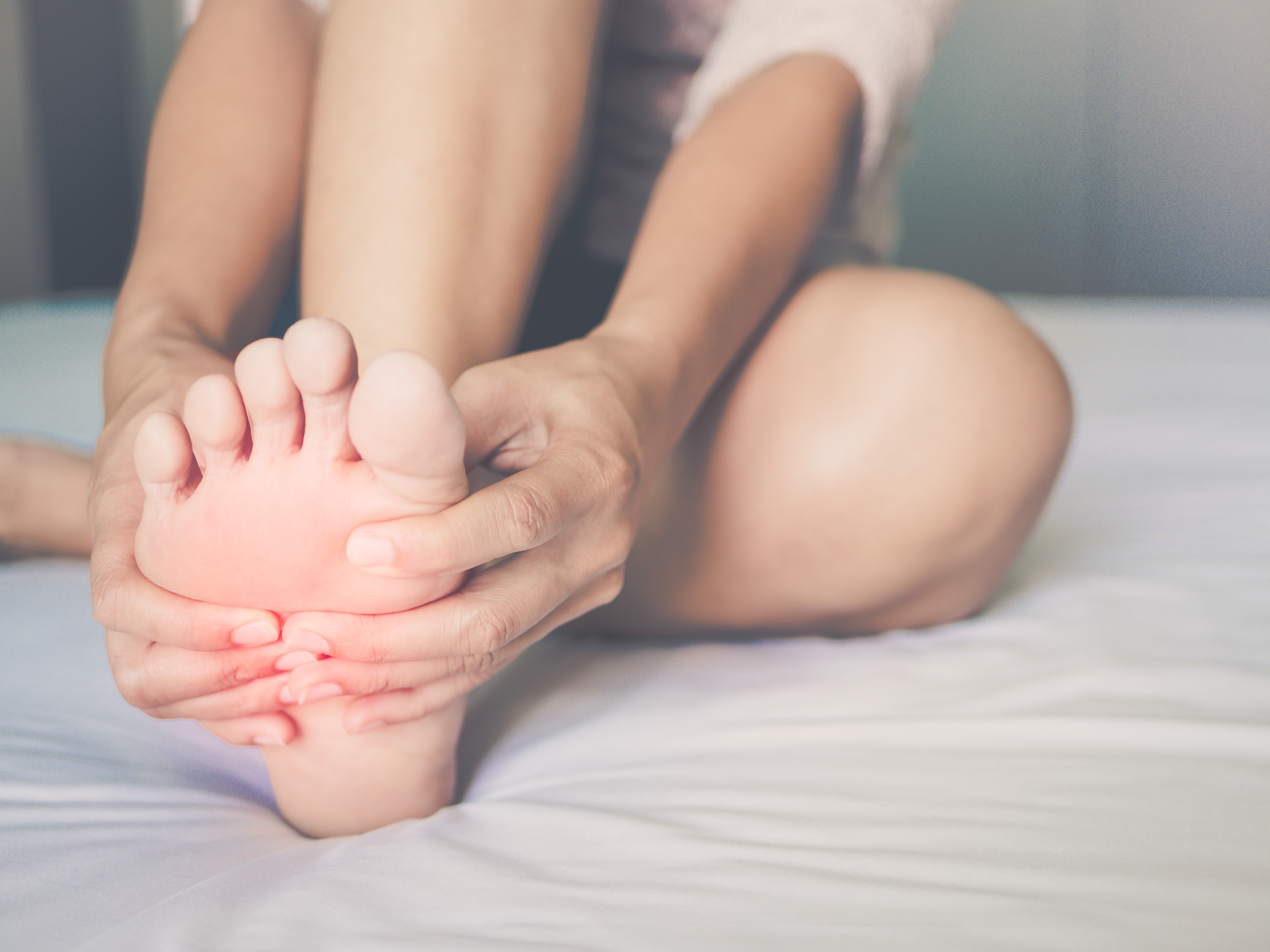 health care concept. woman massaging her painful foot, red hi-lighted on pain area