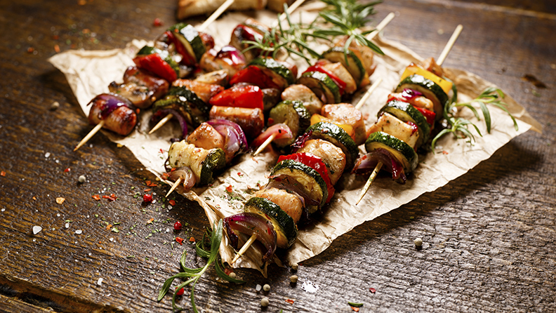 Grilled skewers with chicken meat, sausages, zucchini, peppers, onions and mushrooms in a herb marinade