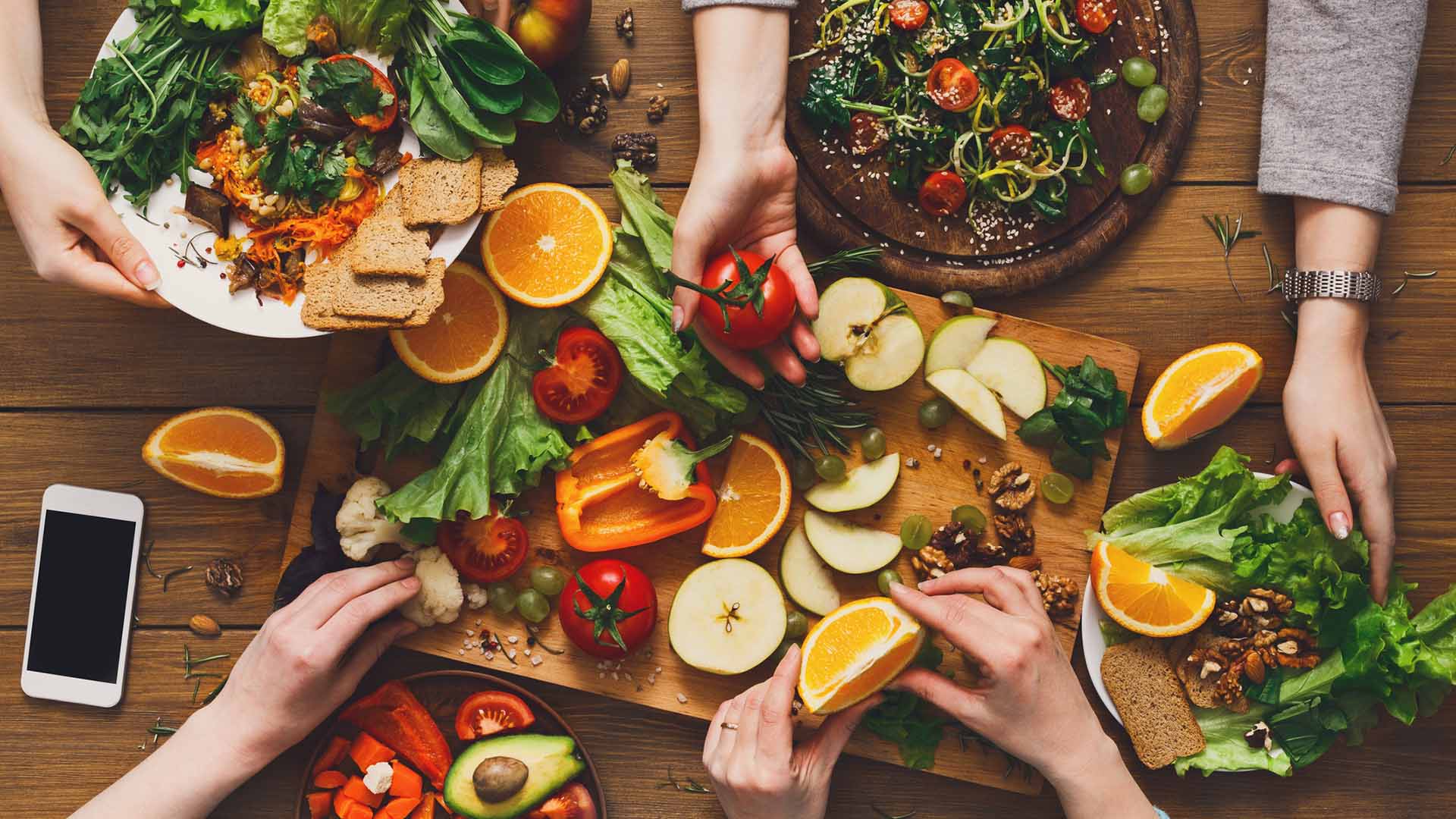 Eating healthy food, fruits and vegetables dinner table. Women at home together, top view, flat lay, crop