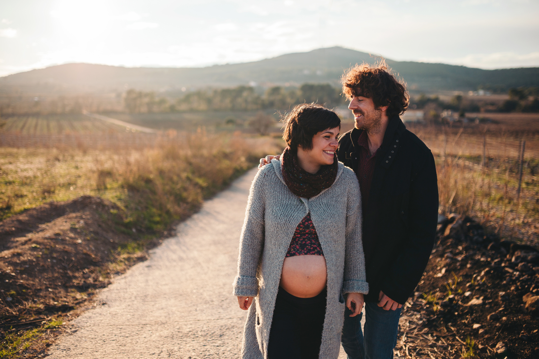 Young couple expecting a baby walking during a sunset