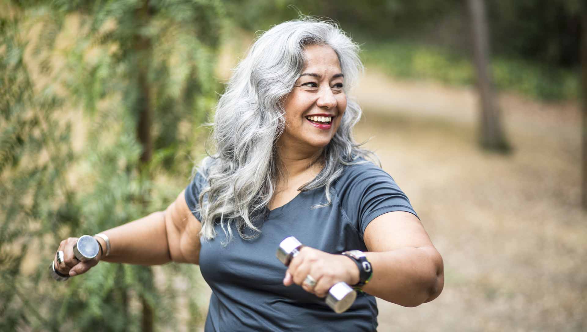 A beautiful senior Mexican Woman working out and stretching with weights